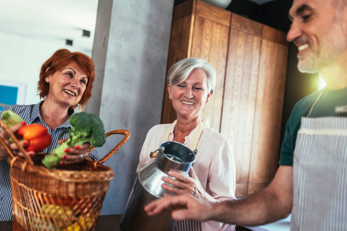 Happy mature middle-aged woman brings fresh vegetables and milk from country to her friends to make healthy dinner