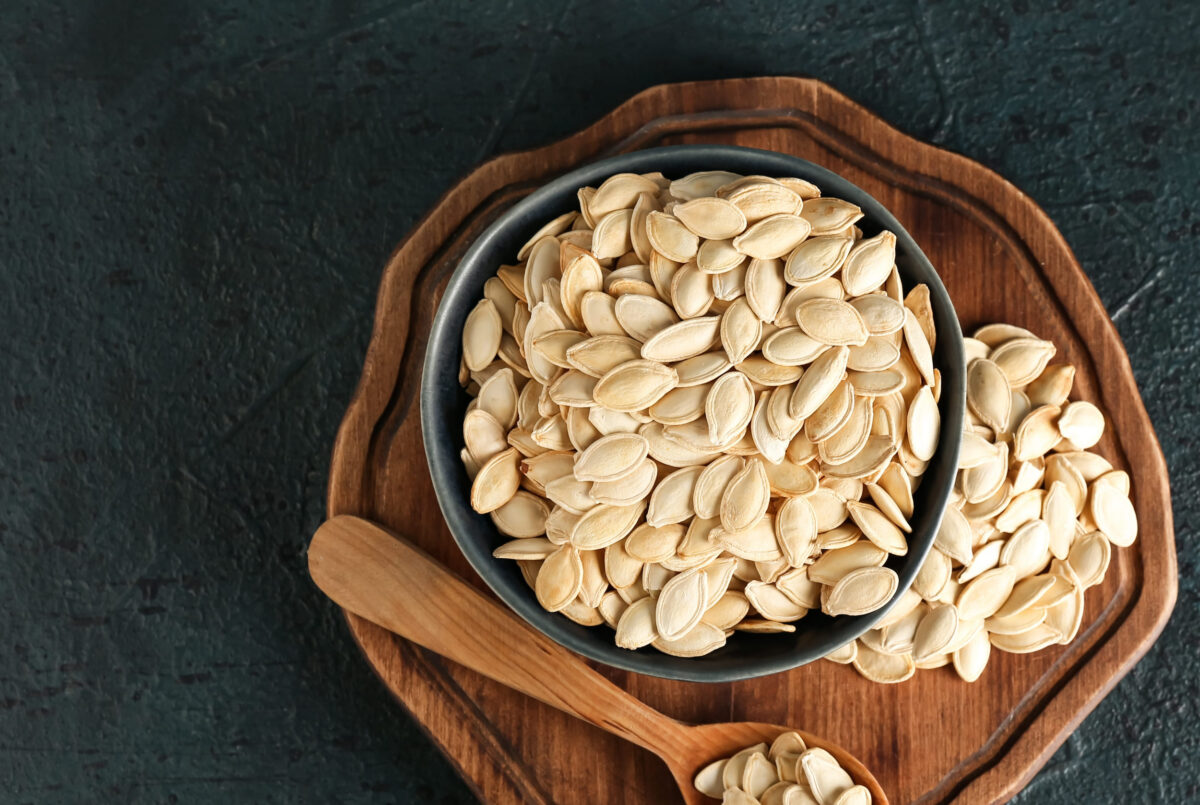 10 Things Families Used to Do With Their Pumpkins After Halloween 1 Bowl and spoon with natural pumpkin seeds on black background