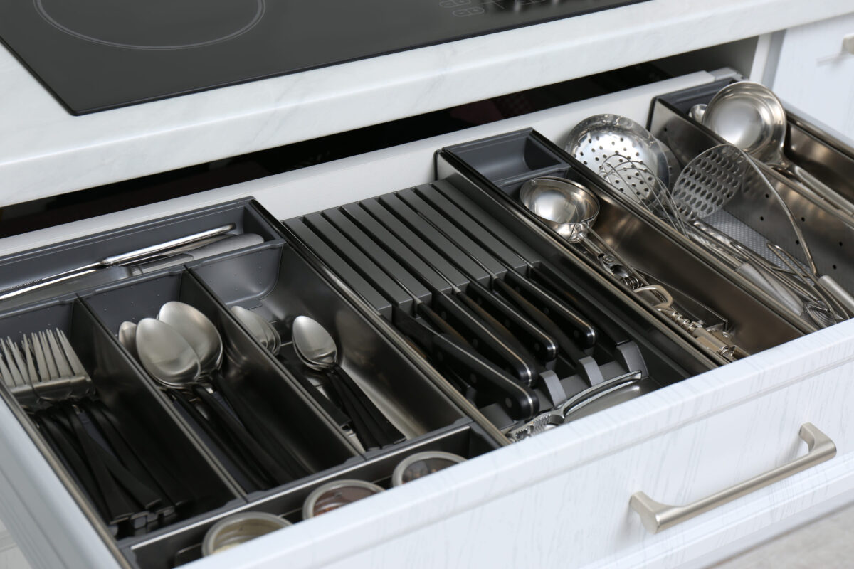Open drawer with stainless steel utensil set, closeup. Order in kitchen