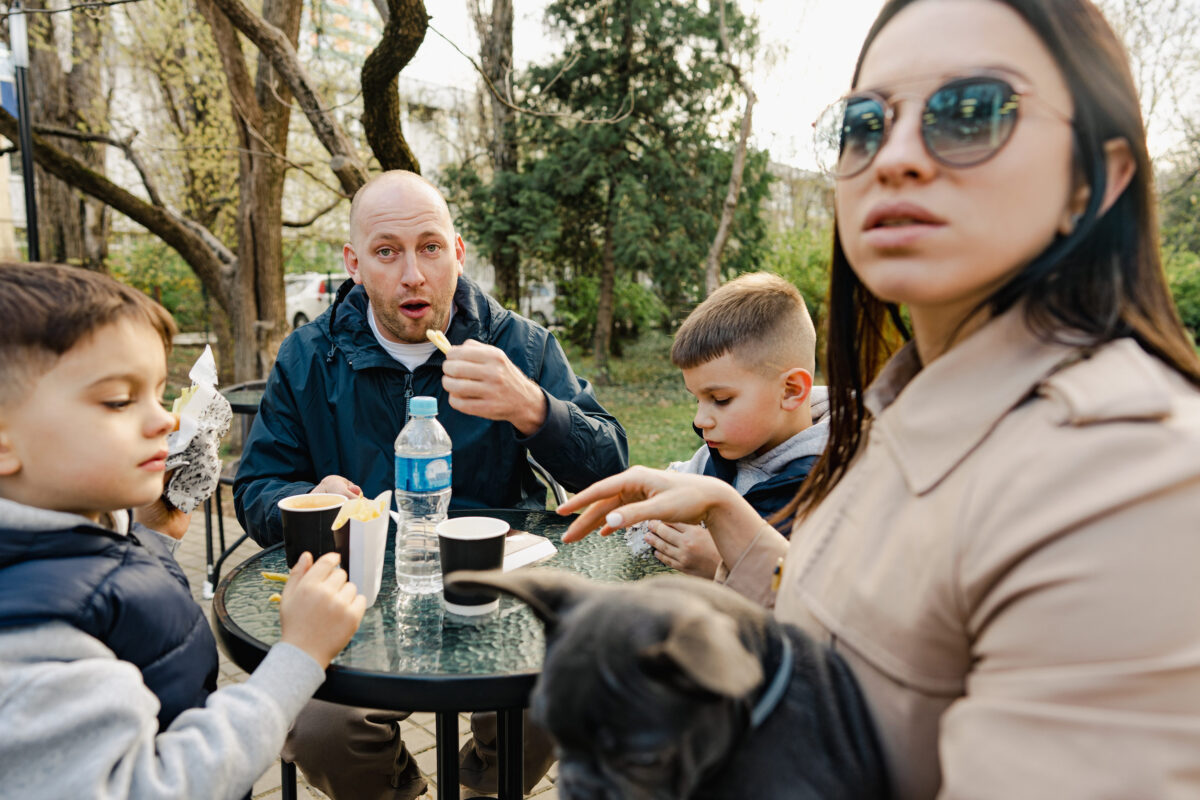 Happy family with two kids having a sancak at outdoor cafe on autumn day