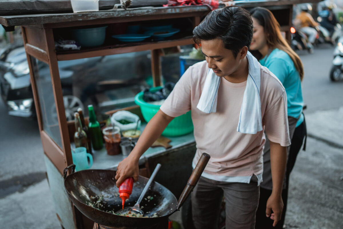 indonesian man putting sauce on fried rice, street food concept