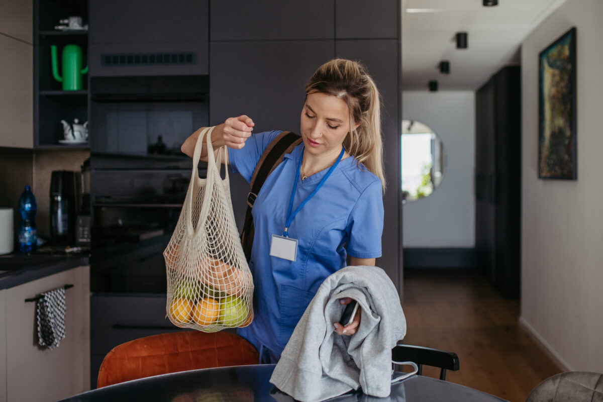 Female nurse returning home from work with groceries for family. Work-life balance of healthcare worker as parent and partner.