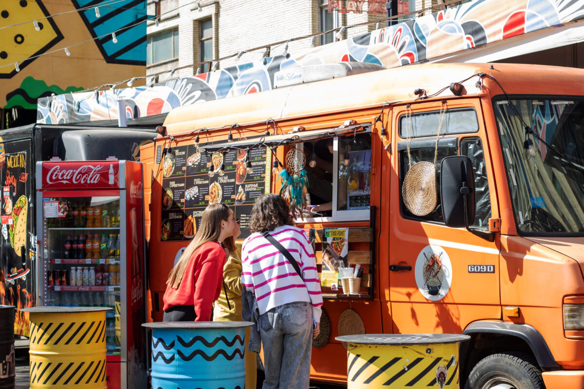 Belarus, Minsk - 05 May 2024: A crowd of people has gathered in front of a food truck to enjoy a meal. The scene is filled with excitement and the aroma of delicious food