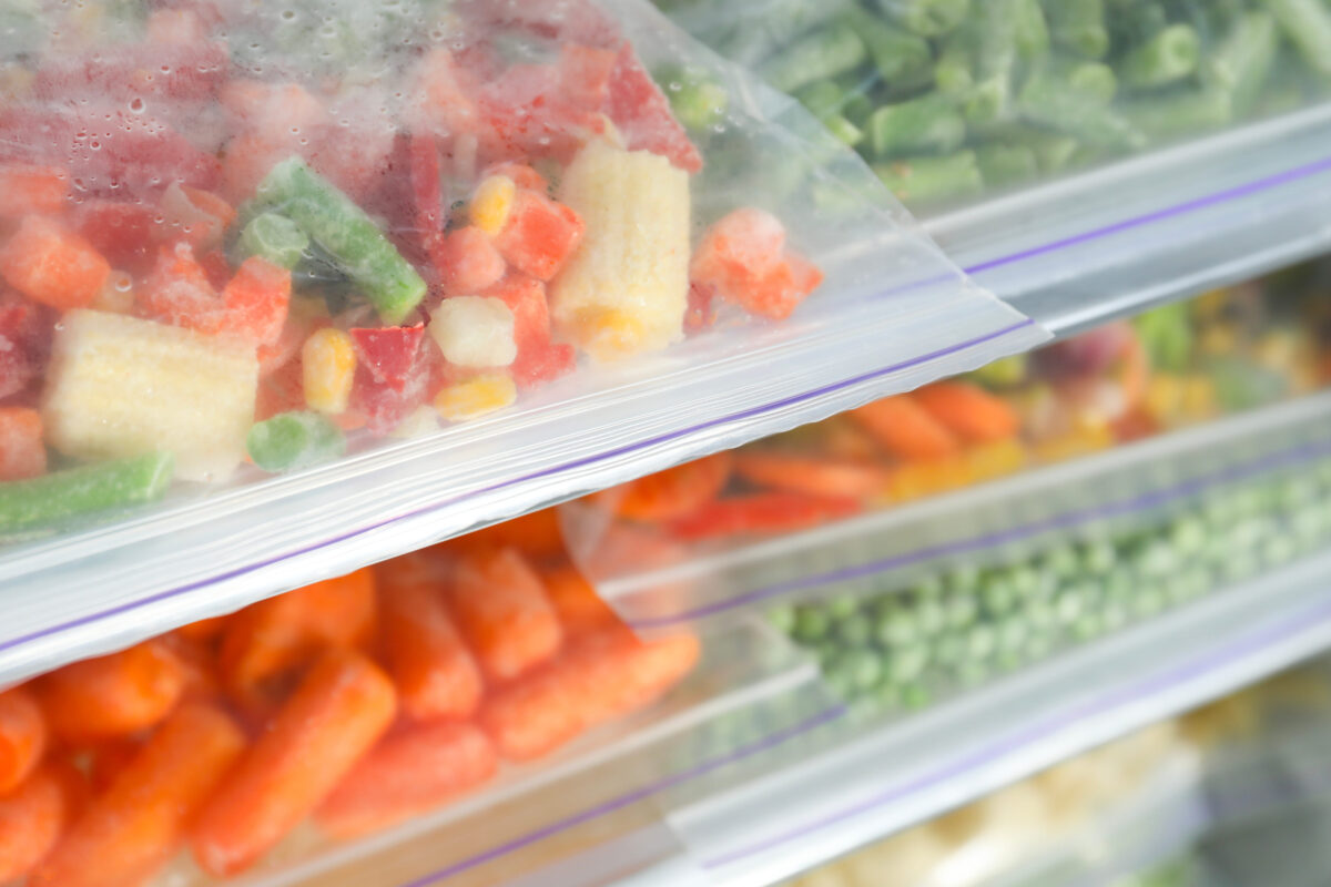 Plastic bags with different frozen vegetables in refrigerator, closeup