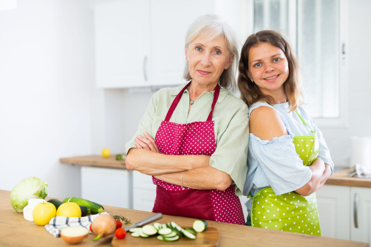 9 Qualities Men May Find More Attractive in a Woman After 50 3 Portrait of elderly woman and her daughter-in-law in an apron in the kitchen - cooking dinner together