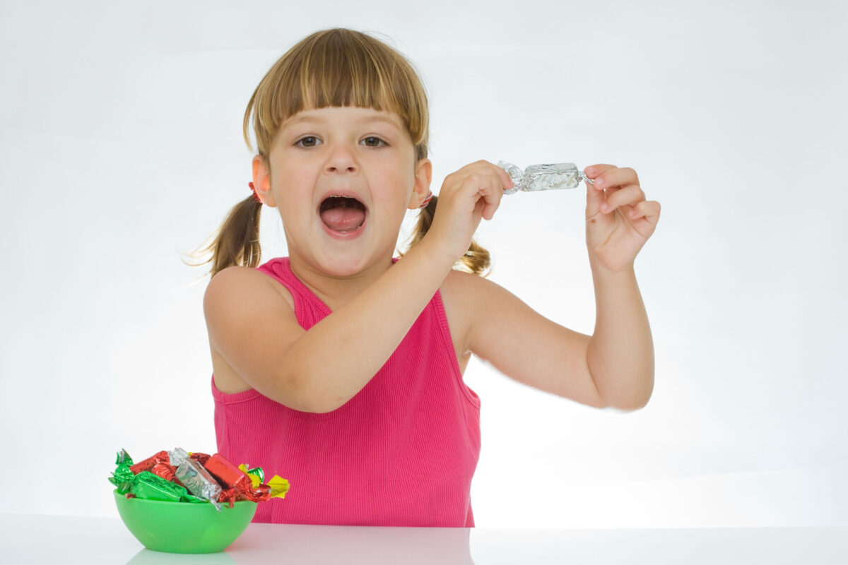 little, pretty girl with chocolate candies, on white