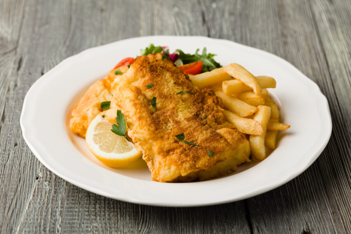 Fried cod with french fries on white plaet.