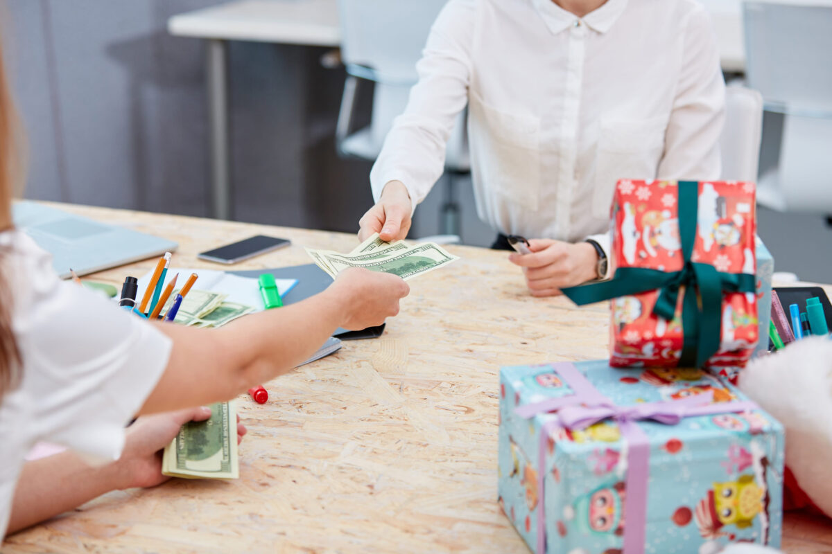 Hands transfer money to other hands on the background of a table with gifts