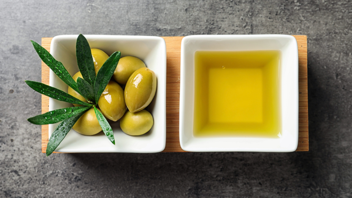 A delightful presentation of green olives paired with a bowl of rich olive oil, garnished with fresh leaves, perfect for enhancing any dish or enjoying as a simple appetizer. Image Credit: 
liudmilachernetska/ 123RF