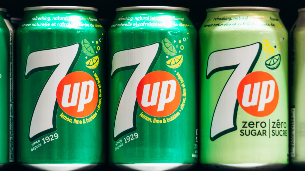 A close-up view of 7UP soda cans displayed on a supermarket shelf in downtown Montreal, showing different varieties and bright green packaging. Image Credit: andreiantipov/ 123RF