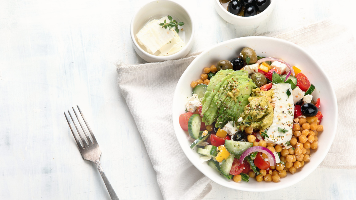 A vibrant, nourishing salad bowl brimming with colorful toppings, featuring creamy avocado, fresh vegetables, and a sprinkle of feta cheese, perfect for a health-conscious meal. Accompanied by olives and a subtle dip, this dish embodies a celebration of flavors and textures. Image Credit: baibakova/ 123RF