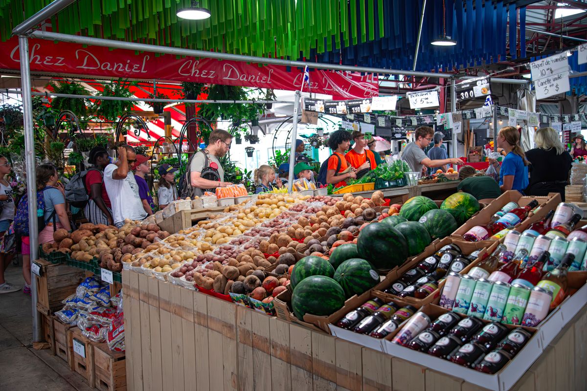 Detroit’s Eastern Market Has Kept People Coming Back Since 1891, and It’s Not Just the Produce 1 A bustling indoor market with diverse produce and shoppers creating a vibrant atmosphere.