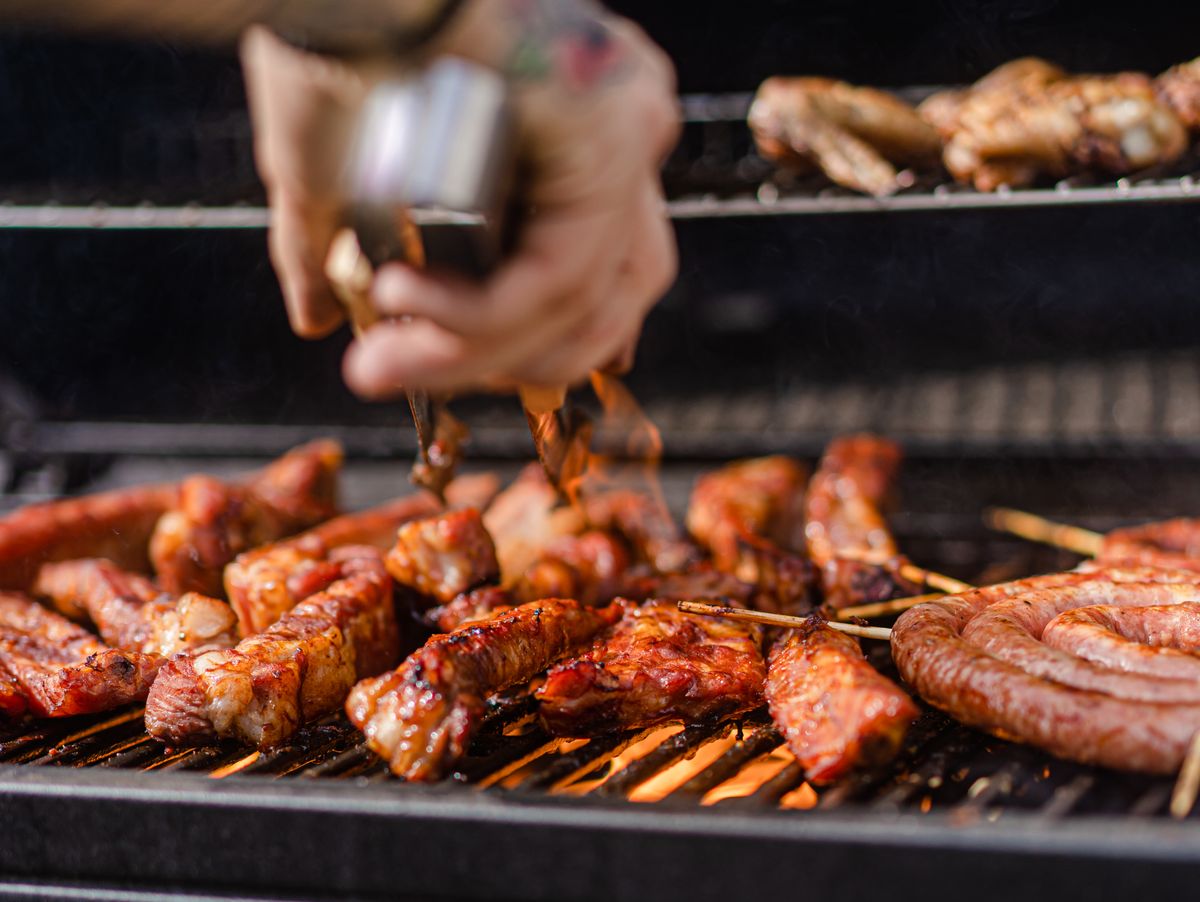 A close-up view of delicious meats and sausages being grilled outdoors.