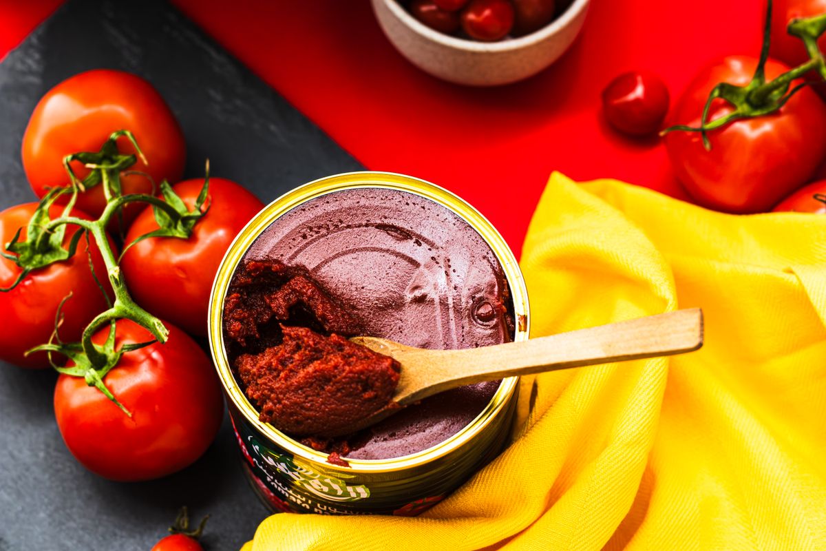7 Canned Foods You Shouldn’t Keep in Your Pantry Forever 1 A colorful flat lay of fresh tomatoes and tomato paste in a bright and artistic presentation.