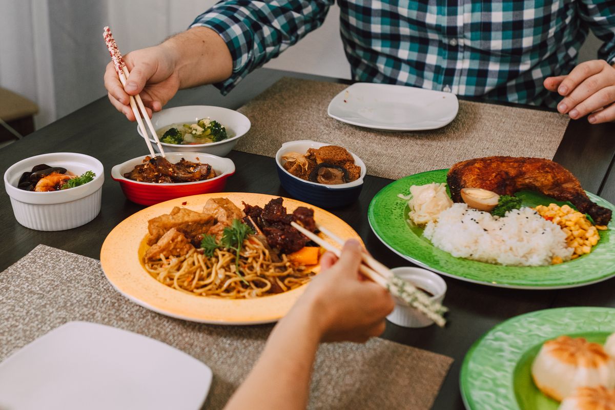 Two Scoops of Rice, One Big Story: How Hawai‘i’s Plate Lunch Became an Island Favorite 2 A delicious Asian meal featuring noodles, meats, and vegetables served with chopsticks on a dining table.