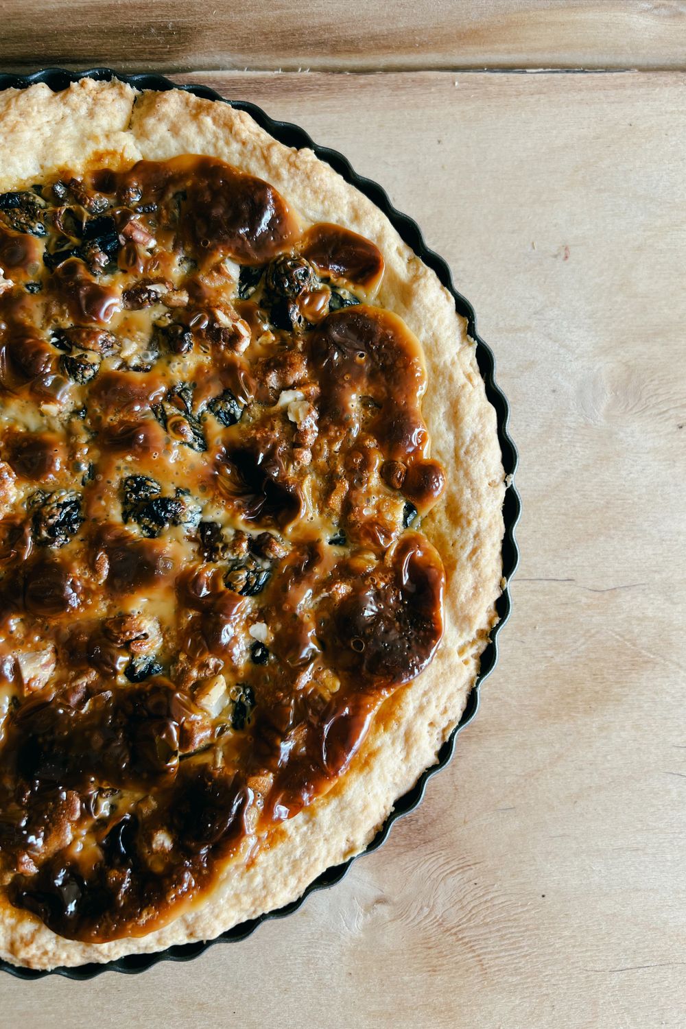 The Secret to a Crisp, Buttery Mushroom and Leek Quiche Starts Before the Filling Goes In 2 A delicious homemade quiche with rich toppings on a rustic wooden surface, perfect for culinary themes.