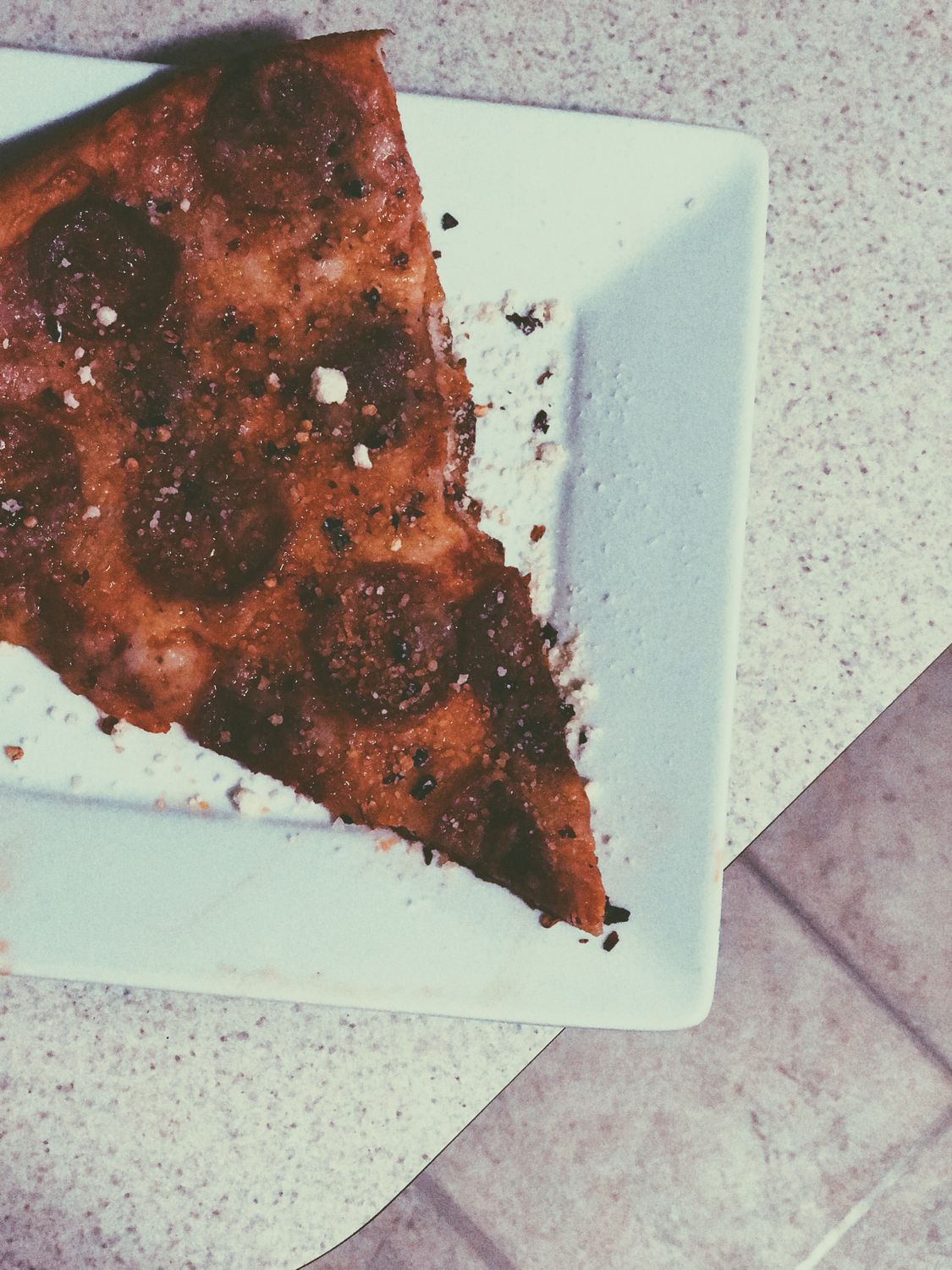 A delicious slice of pepperoni pizza on a white plate, dusted with seasoning.