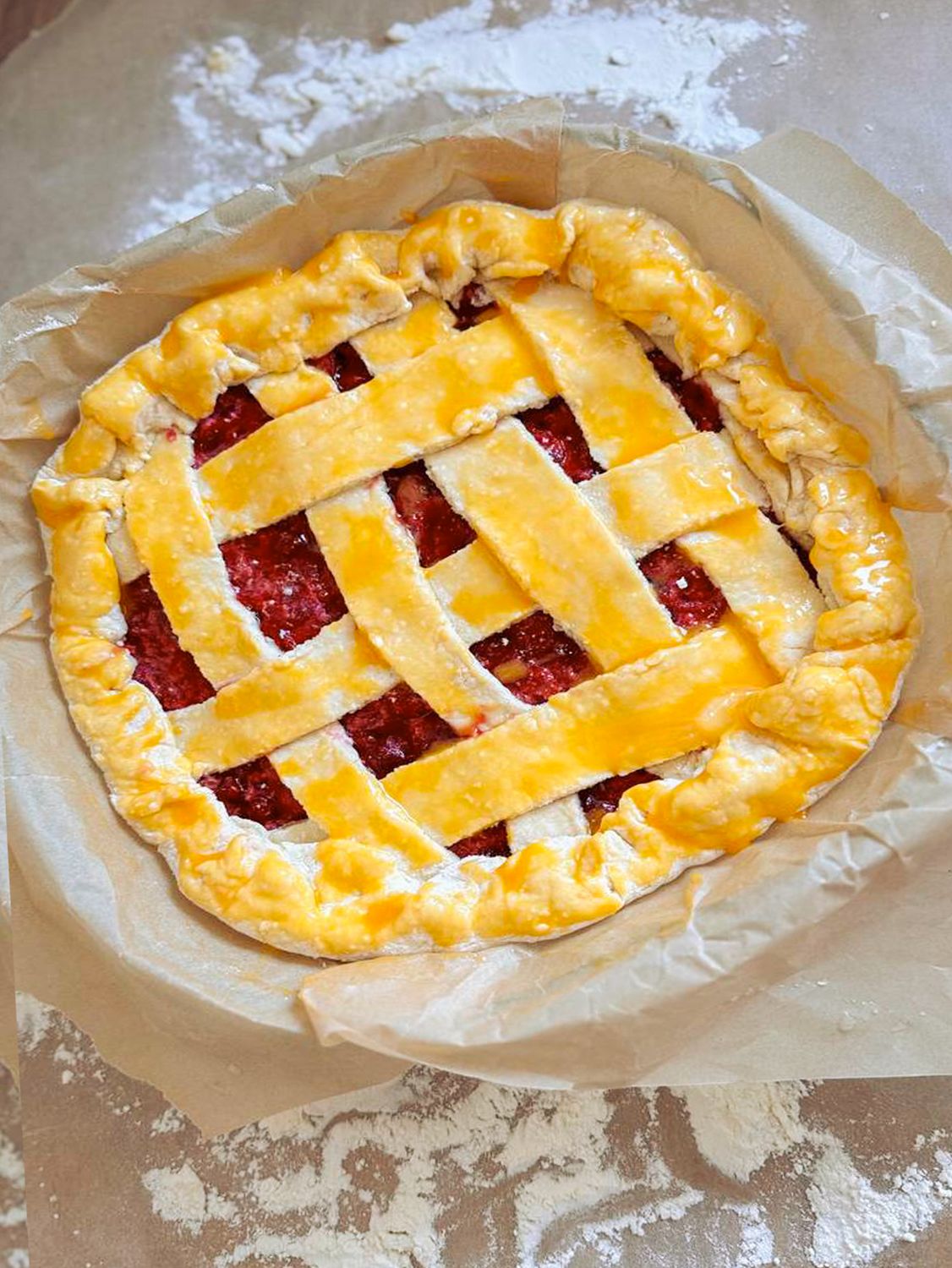 A freshly baked lattice cherry pie on parchment paper showcasing its golden crust.