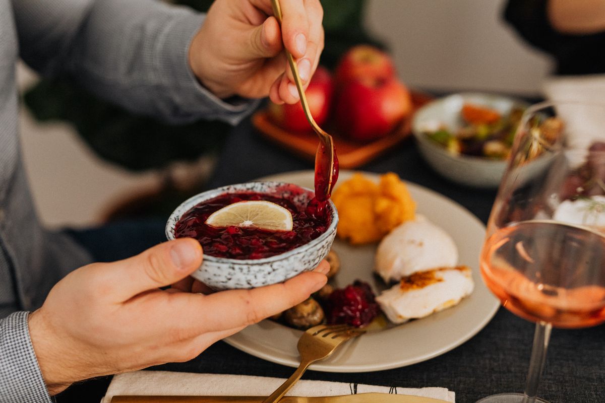 A man enjoys an elegant dinner with cranberry sauce, showcasing fine dining.