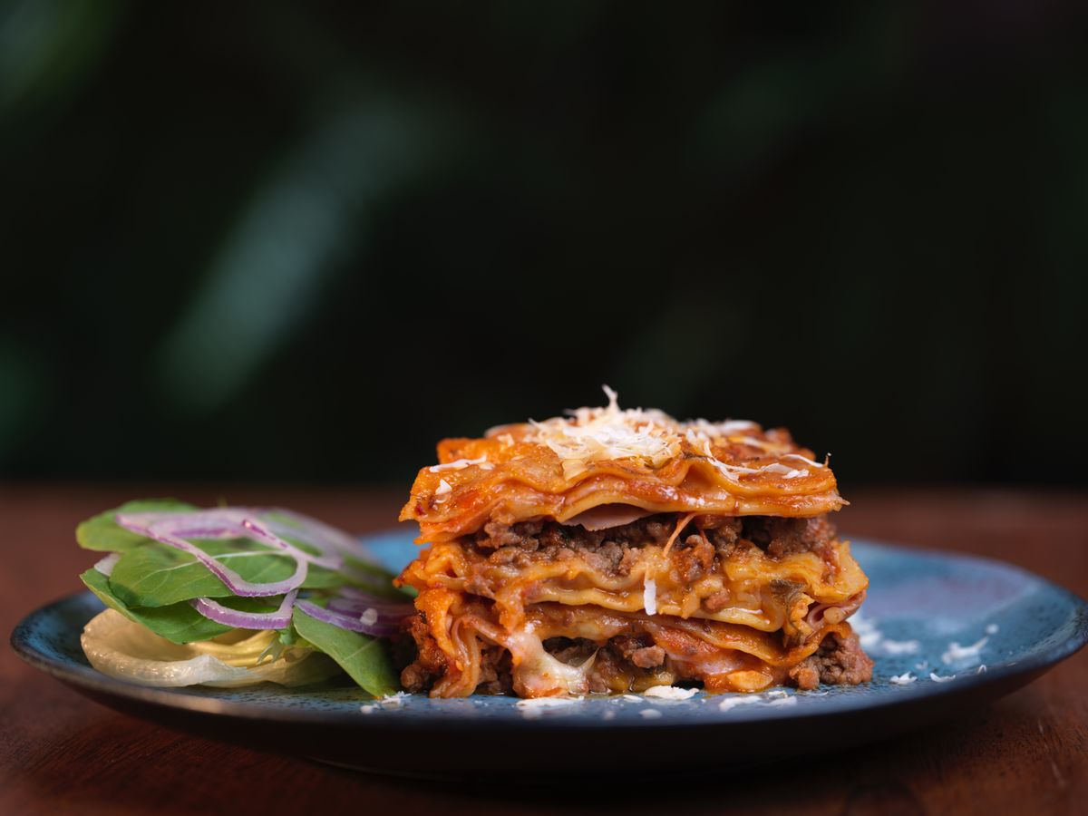 A mouth-watering slice of traditional Italian lasagna served with a side of fresh salad.