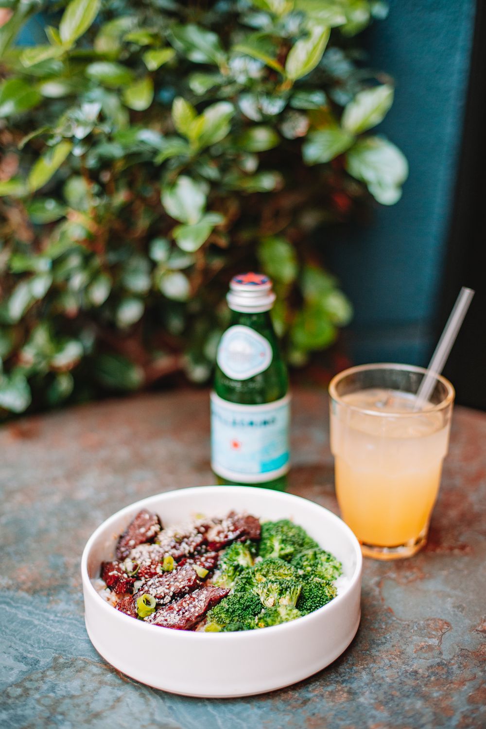 A nutritious meal with broccoli, meat, and juice served in a cozy setting.