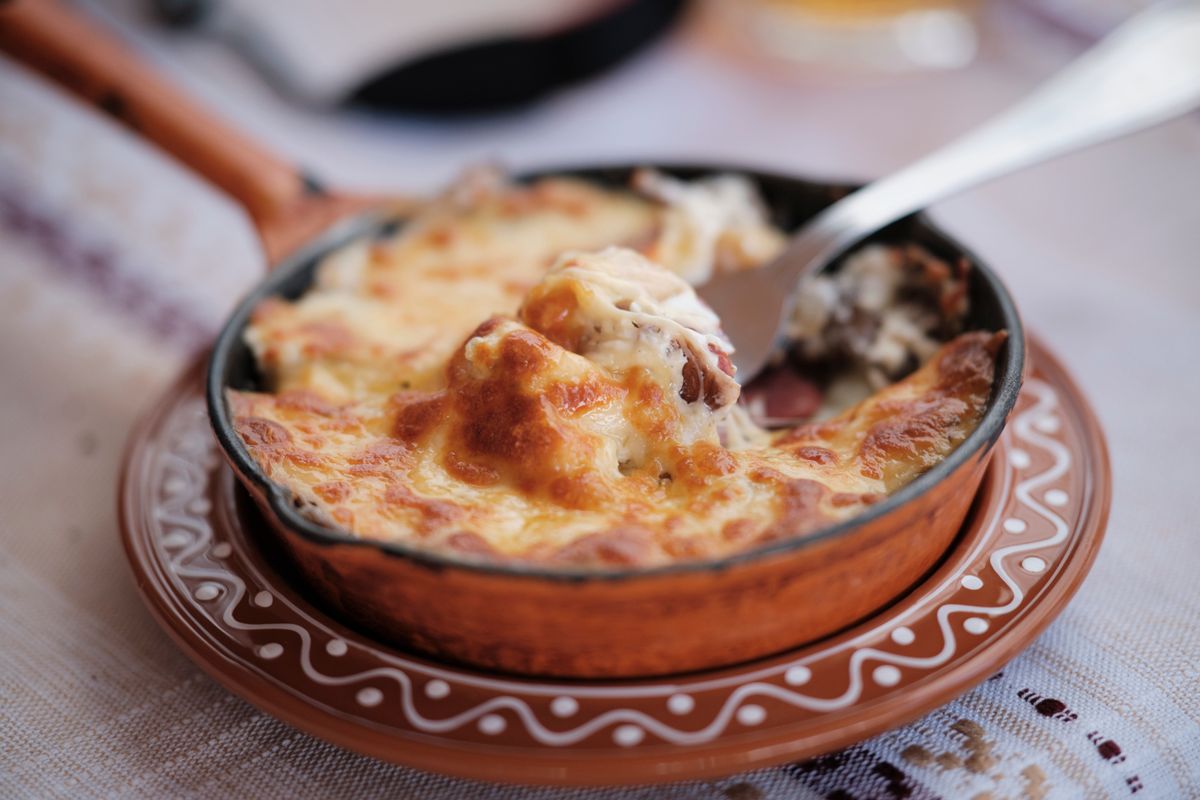 A perfectly baked cheesy dish in a rustic ceramic pot with a golden crusty top.