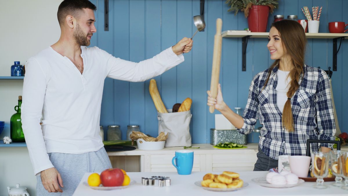 A playful moment in a modern kitchen with cooking tools and fresh food.