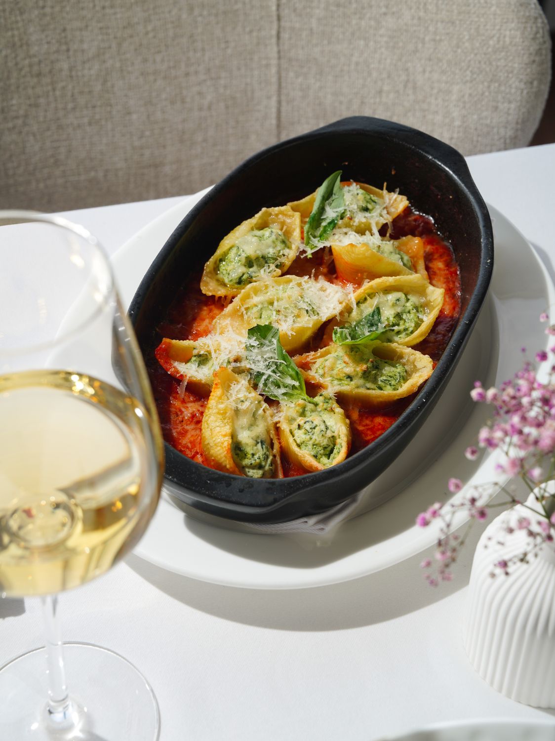 A savory plate of stuffed pasta shells with spinach and cheese served alongside a glass of white wine.