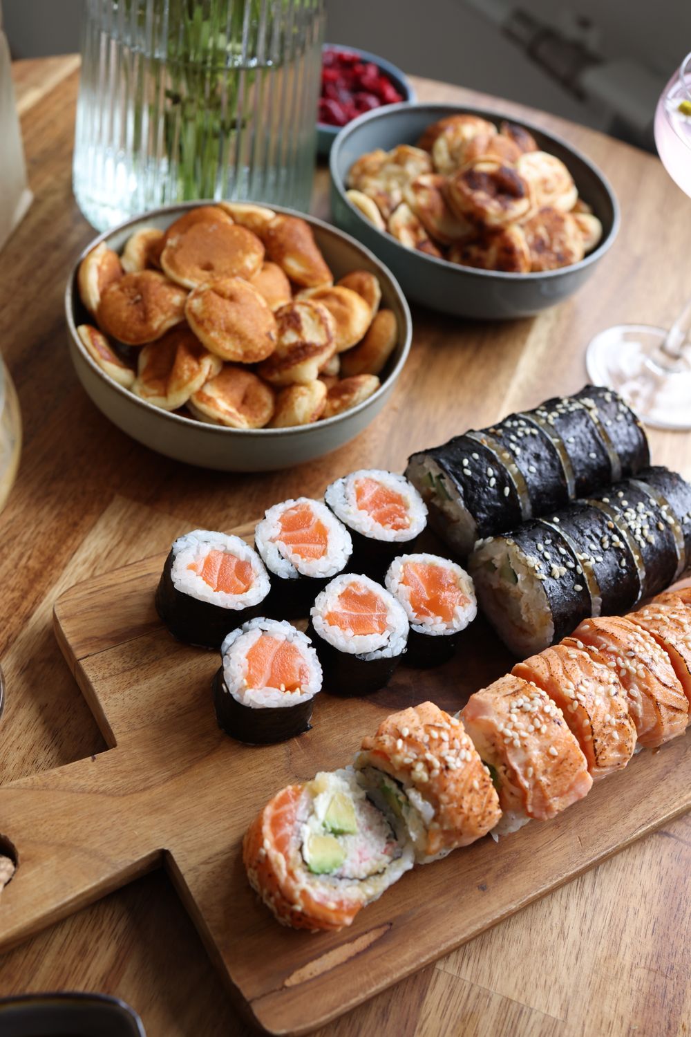 A selection of sushi rolls and snacks on a wooden platter, perfect for any meal.