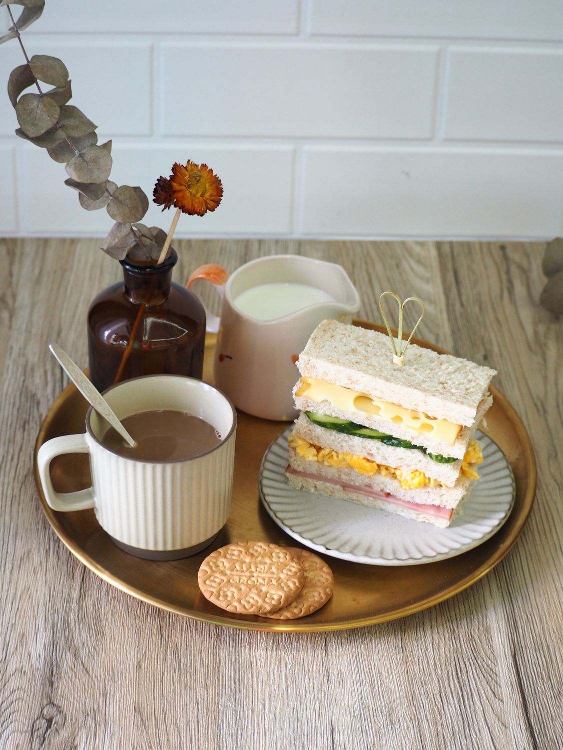 A stylish breakfast scene featuring layered sandwiches, biscuits, and a mug of hot chocolate.