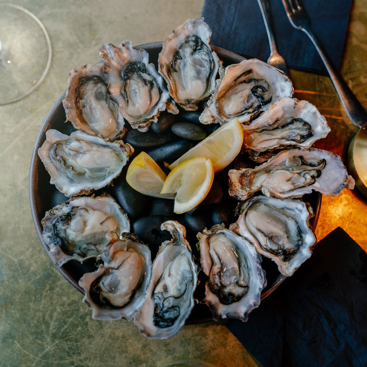 A top view of fresh oysters on a platter with lemon wedges, ready to serve.