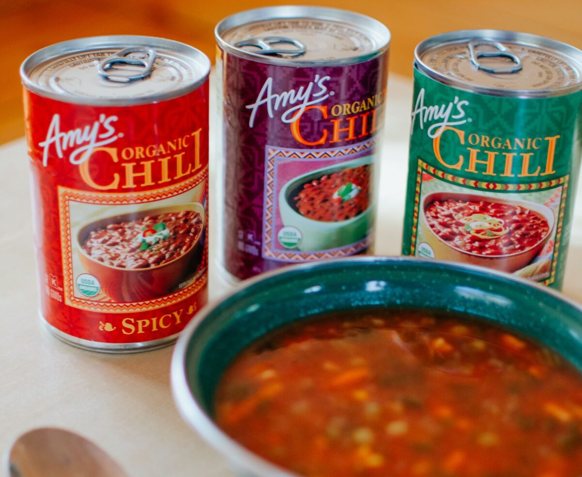 5 Pantry Staples That Make Cooking Optional 1 A vertical shot of organic chili served in a ceramic bowl, with canned chili options nearby.