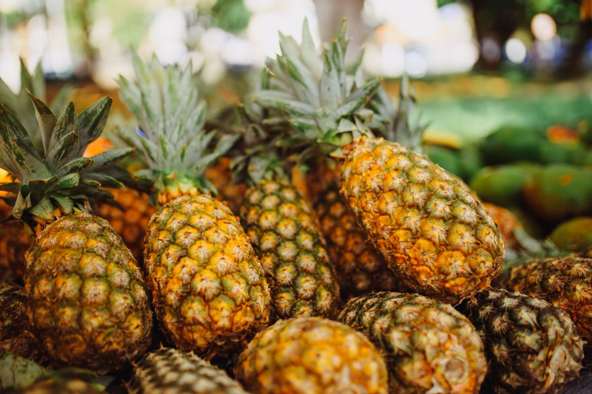 A vibrant display of fresh pineapples at an outdoor market, showcasing their rich texture and color.
