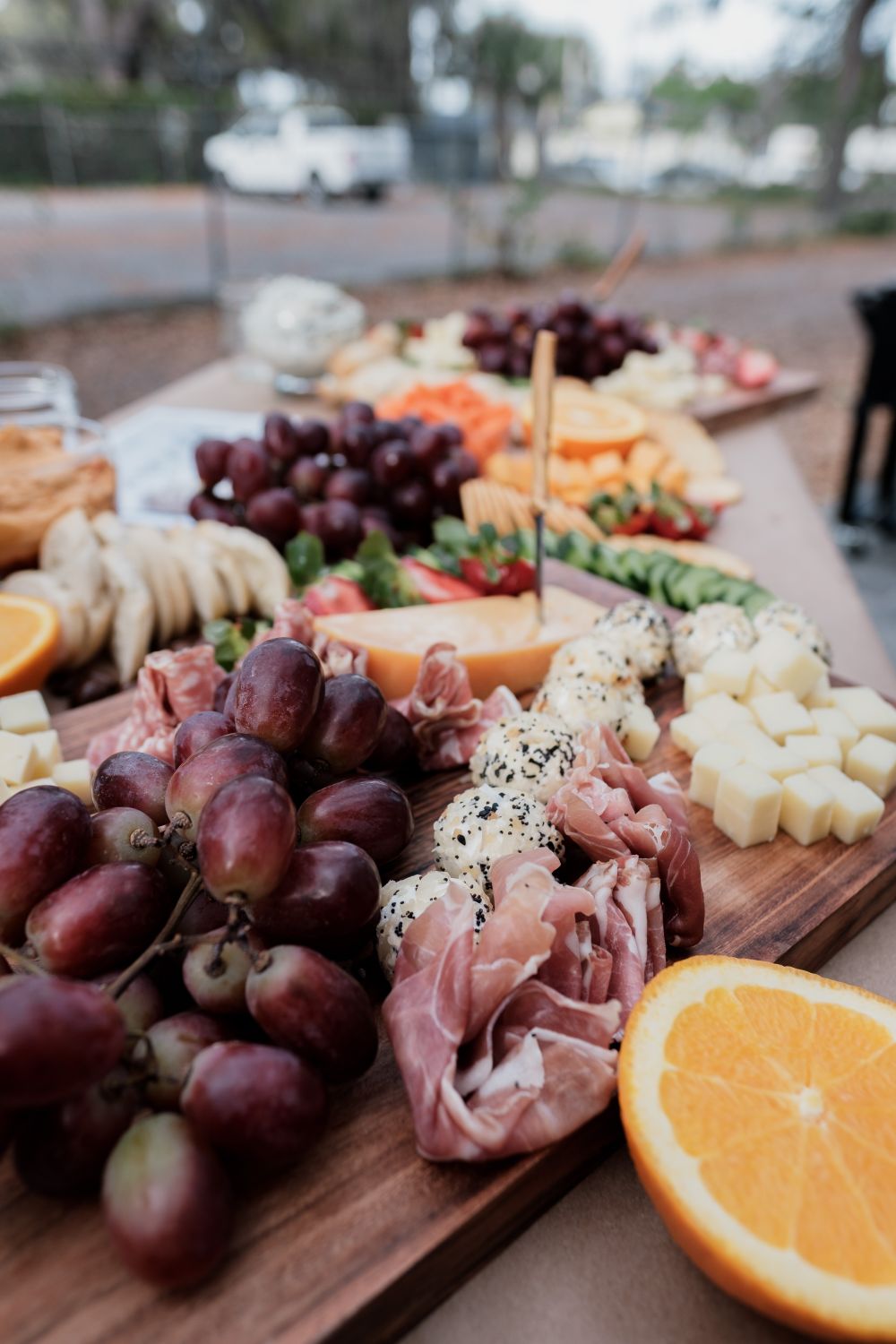 Why Roasting Grapes Can Turn an Ordinary Cheese Board Into Something Special 1 A vibrant outdoor charcuterie board featuring fresh grapes, cheeses, meats, and sliced fruits.