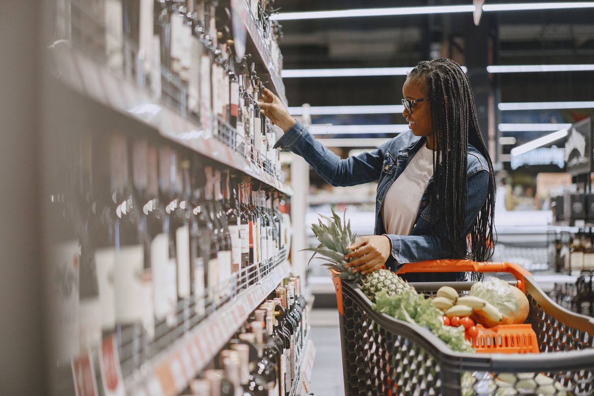 8 Grocery-Store Hot Sauces, Ranked and the Winner Might Start a Fight at Dinner 2 A woman shopping for wine and groceries, filling her cart with fresh produce.