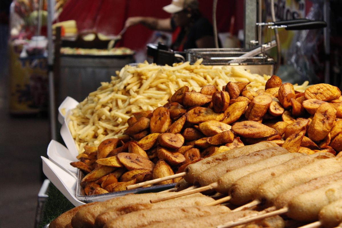 An appetizing display of street food with fried plantains, corn dogs, and French fries.