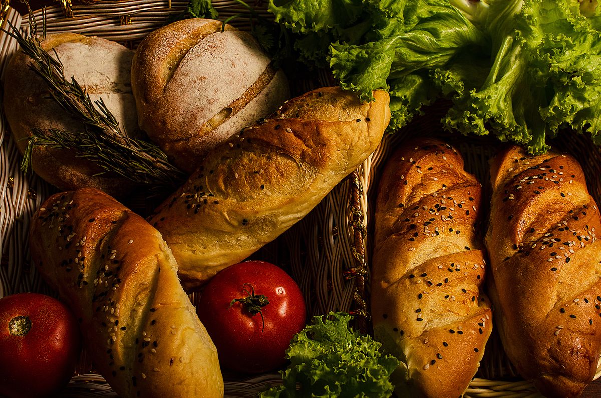8 Everyday Foods That Can Contain Dairy, Even Without a Cheesy Flavor 1 Assorted breads with fresh vegetables in a basket, showcasing a rustic and healthy meal.