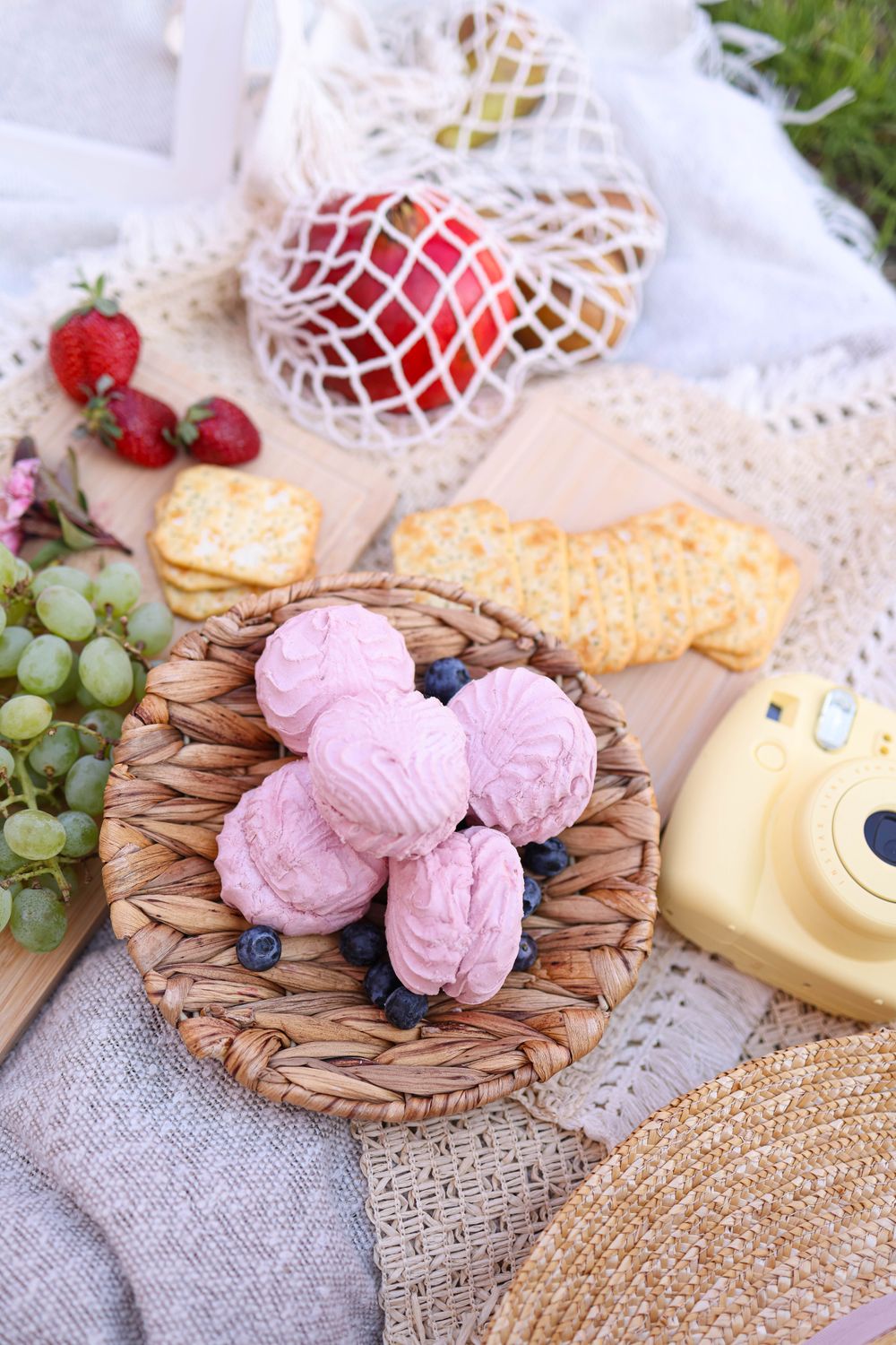 These Homemade Strawberry Marshmallows Get Their Pretty Pink Color From Real Fruit 2 Basket of pink meringues with blueberries at a cozy outdoor picnic setting with fruits and snacks.