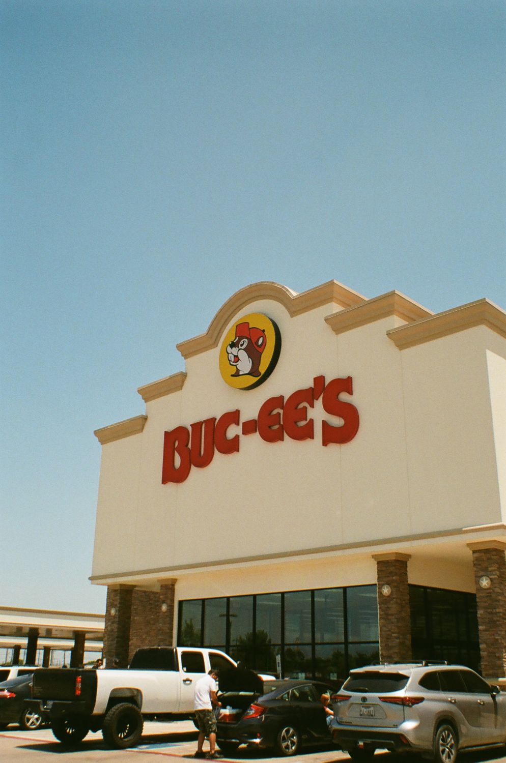 Buc-ee's storefront showcasing its iconic branding under a clear blue sky with parked vehicles.