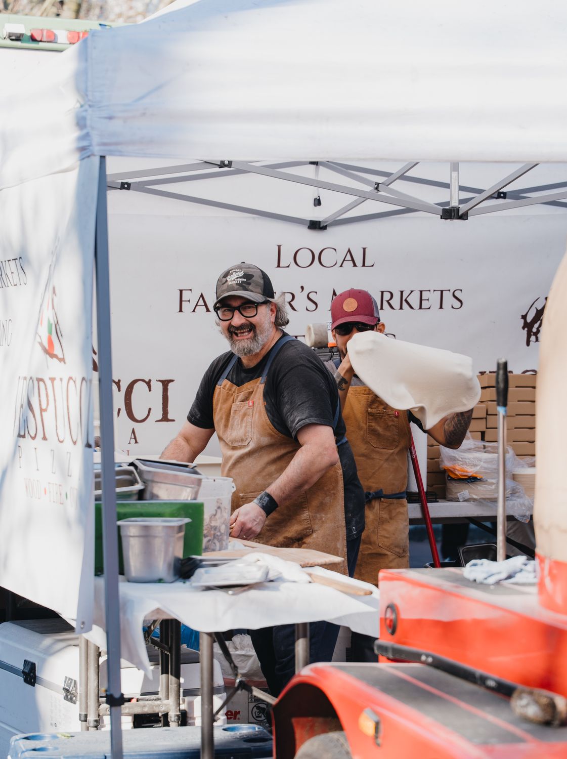 Cheerful vendors at a Seattle farmers market preparing artisan foods.