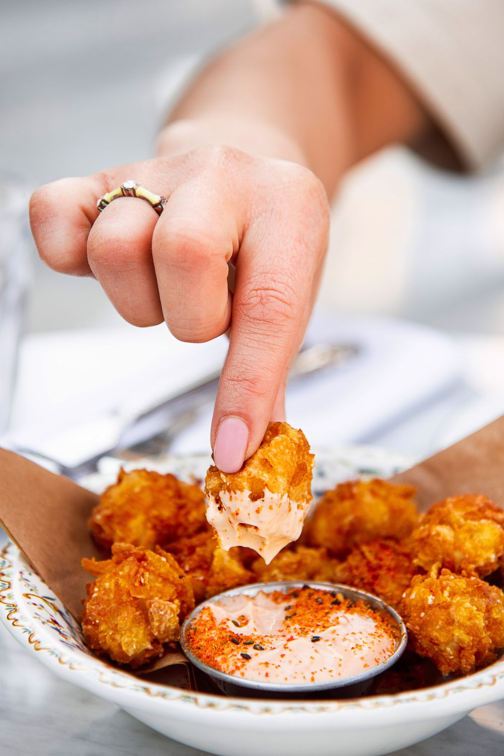 Close-up of a hand dipping fried food into spicy sauce, highlighting a crispy, delicious snack.