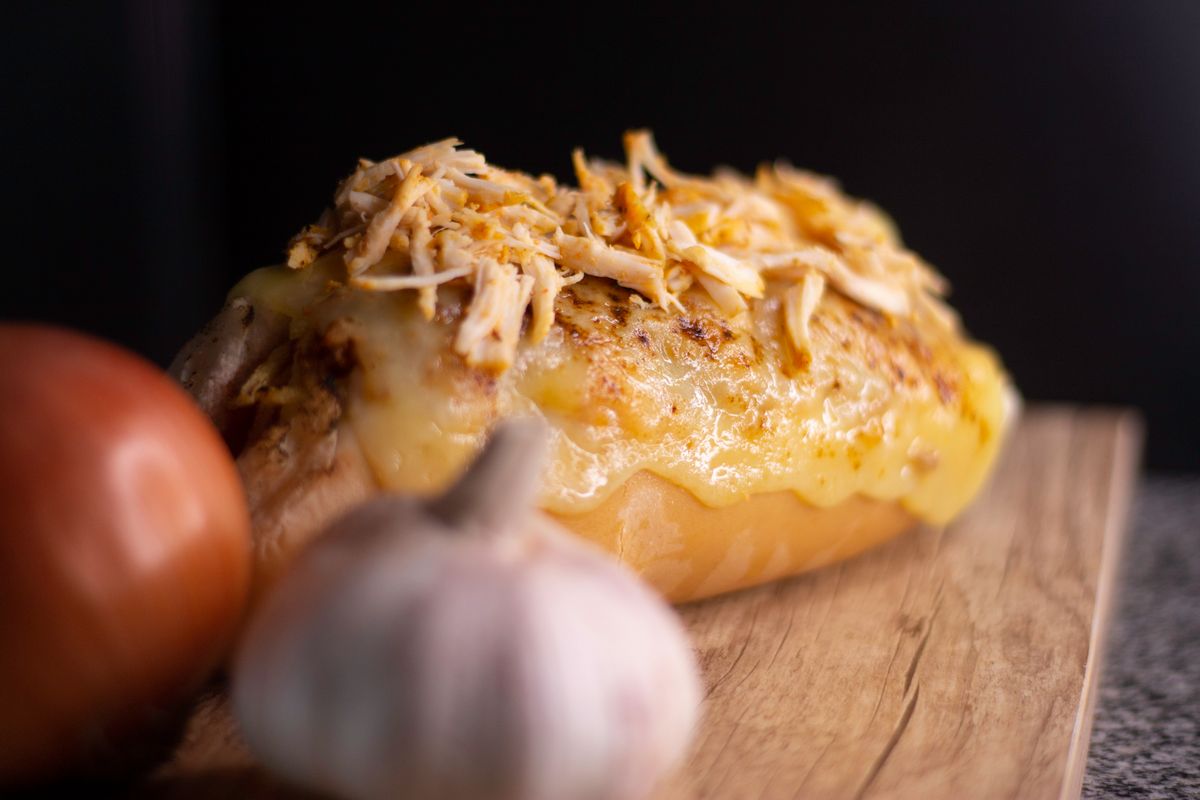 Close-up of a savory cheesy chicken bread with garlic and onion on a wooden board.