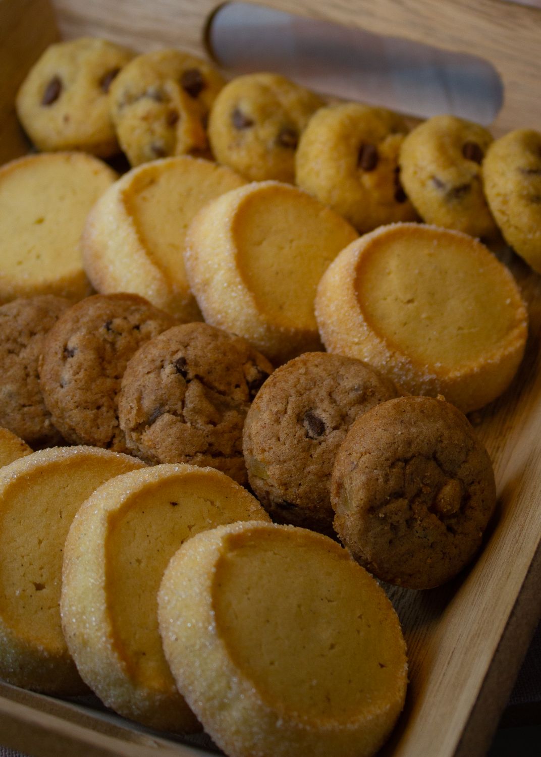 Close-up of assorted homemade cookies displayed on a wooden tray, showcasing variety and texture.