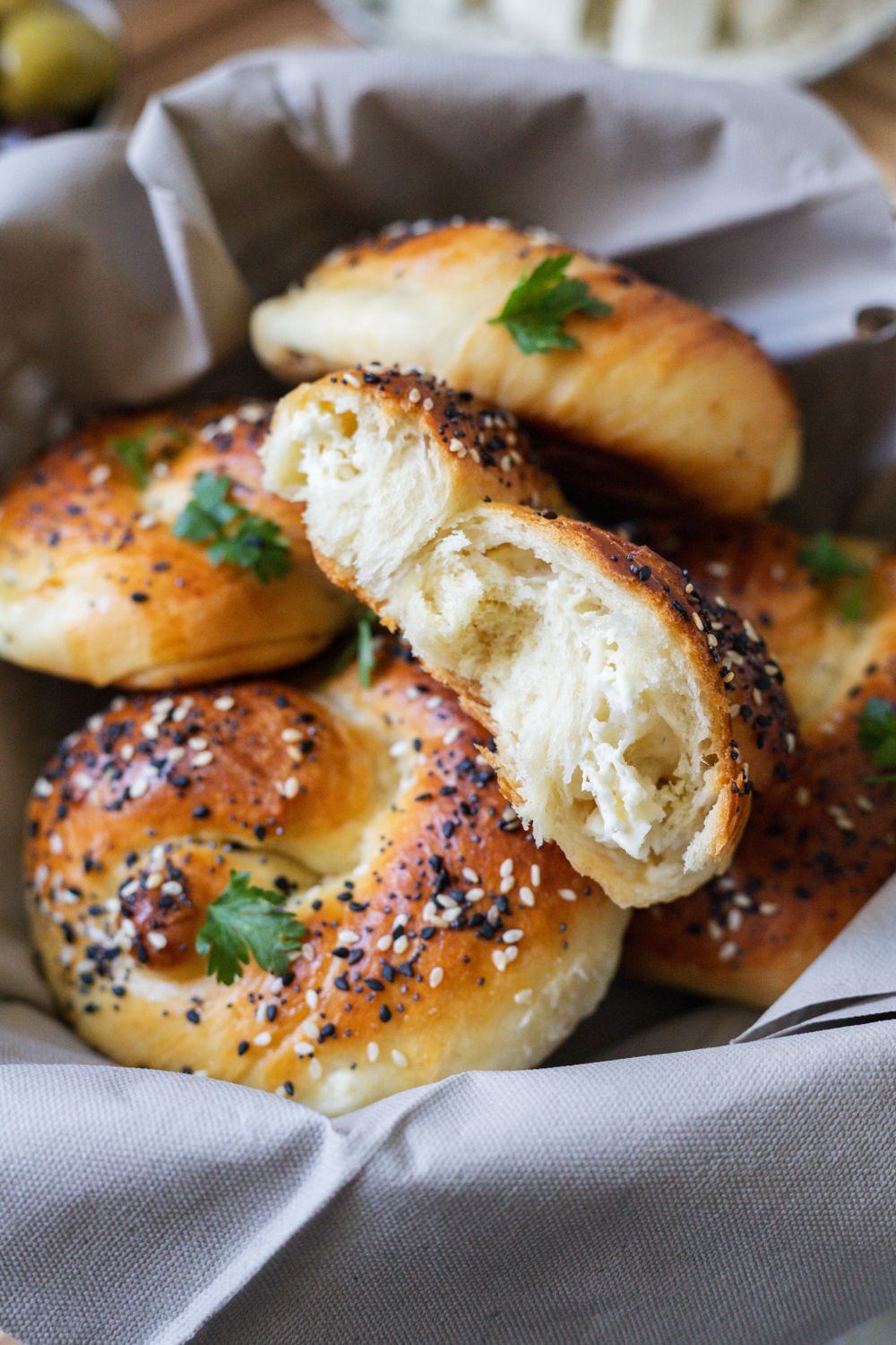 Close-up of freshly baked bagels topped with sesame seeds and herbs in a basket.