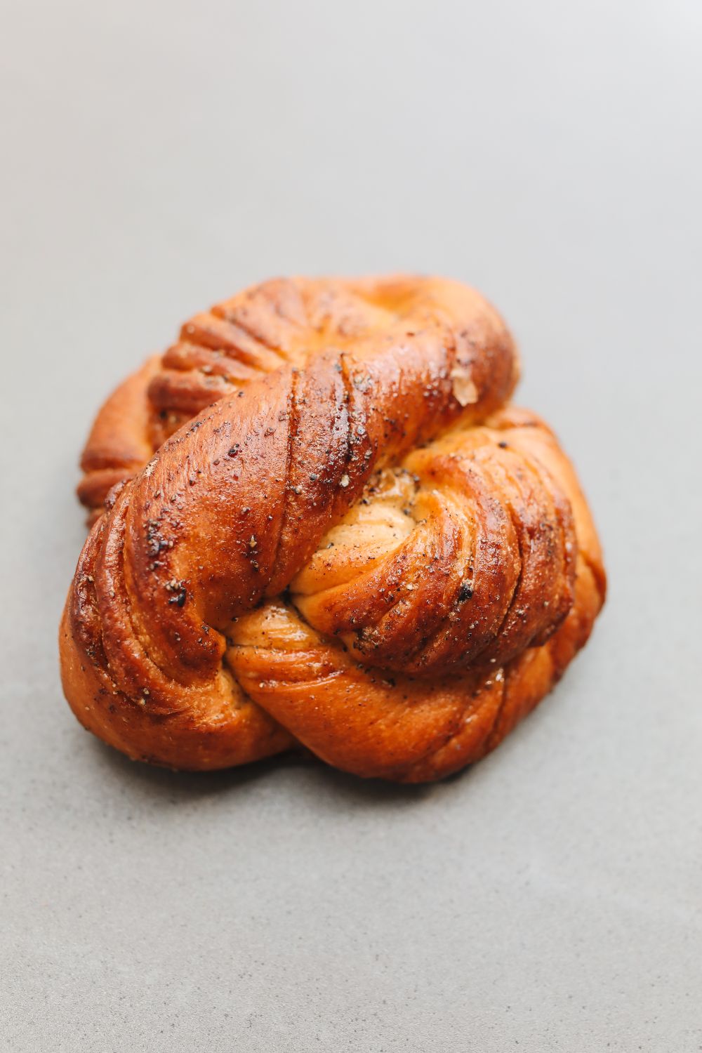 Close-up of freshly baked cardamom knot bread on a neutral background.