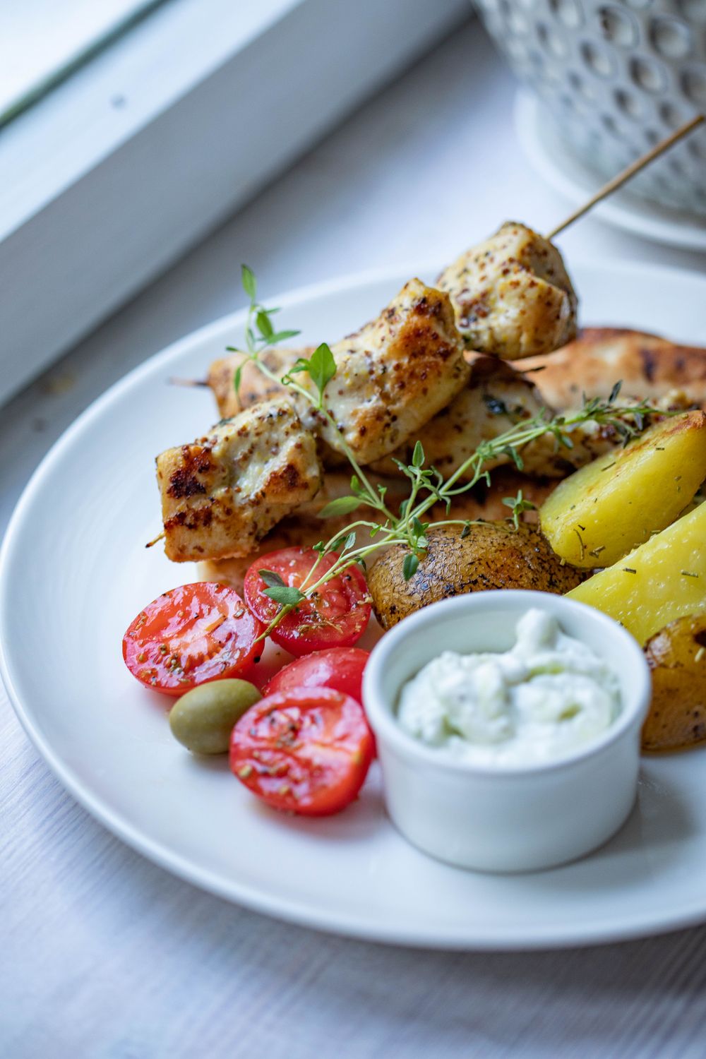 Prunes and Olives in Your Chicken Dinner? This Retro Classic Makes a Delicious Case 2 Close-up of grilled chicken kebabs with vegetables and dip on a white plate.