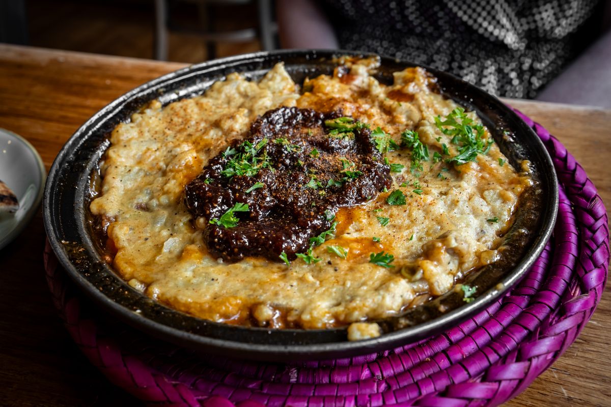 Close-up of lamb served on mashed potatoes garnished with parsley on a rustic plate.