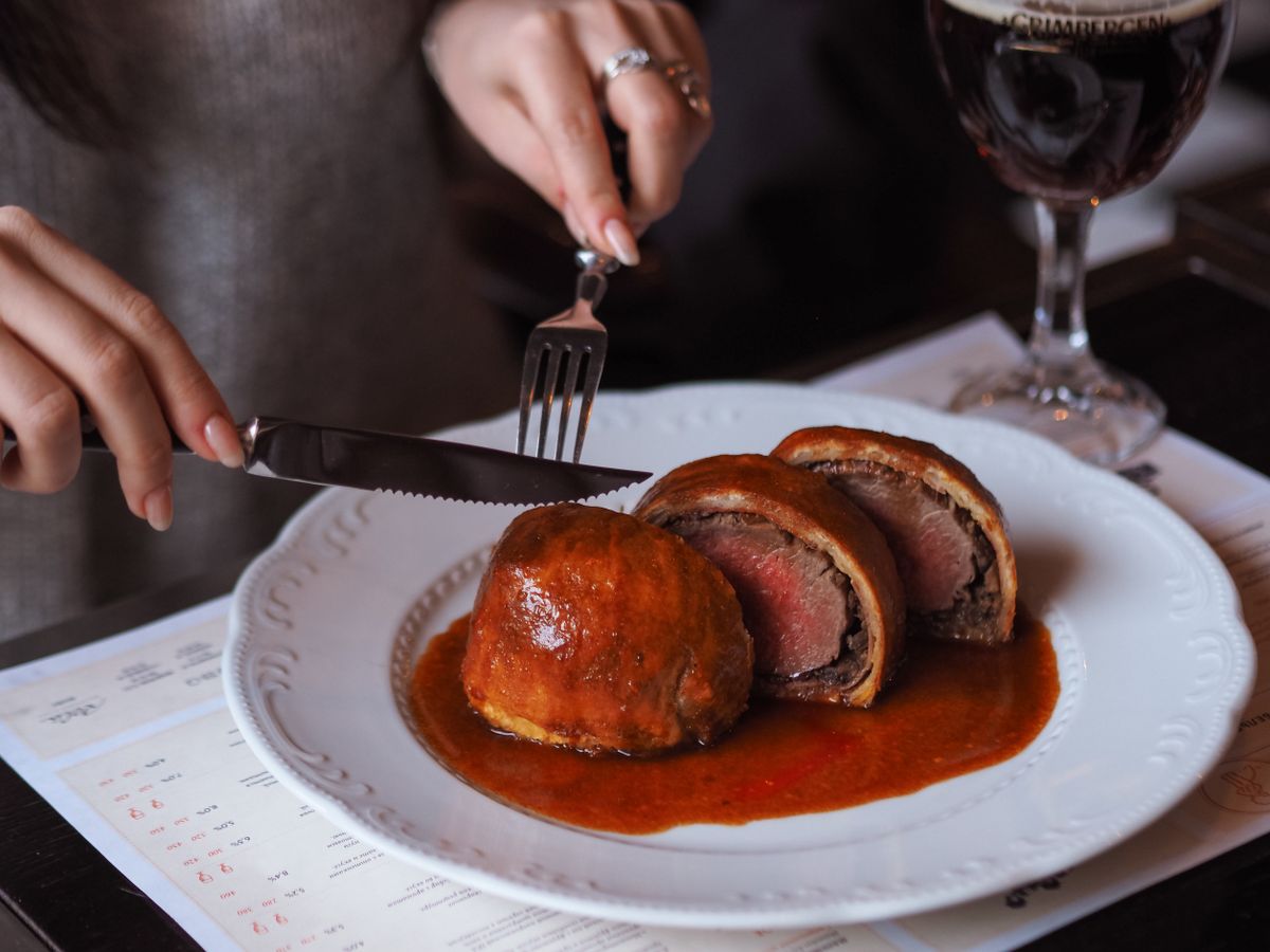 7 Classic Dishes That Make You Work for Every Bite 1 Close-up of sliced Beef Wellington on a plate, showcasing gourmet dining experience indoors.