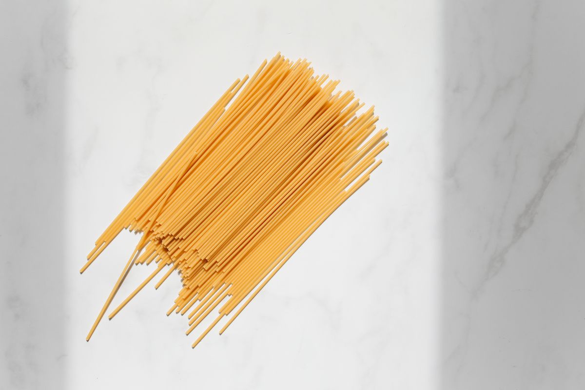 Close-up view of uncooked spaghetti arranged on a white marble surface, ideal for culinary themes.