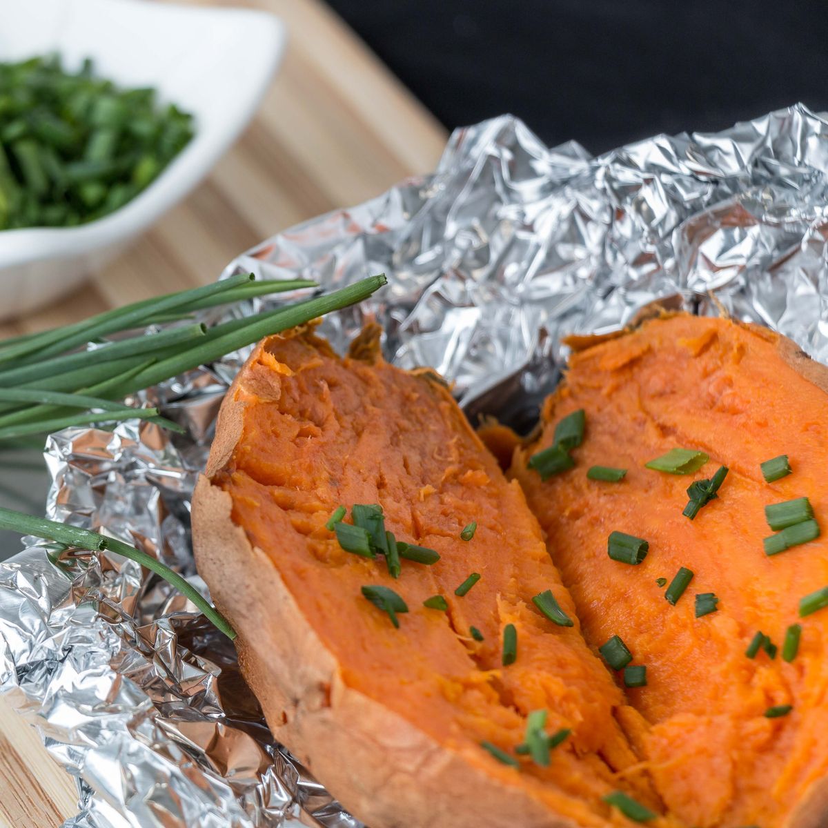 The Foil-Packet Salmon Dinner That Keeps Cleanup to a Minimum 2 Delicious baked sweet potato garnished with fresh chives in foil.
